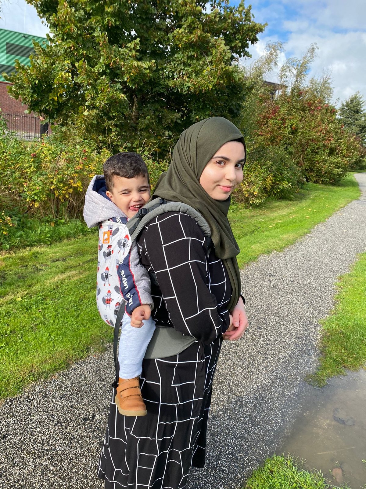 Lachende peuter die op de rug wordt gedragen op een wandelpad