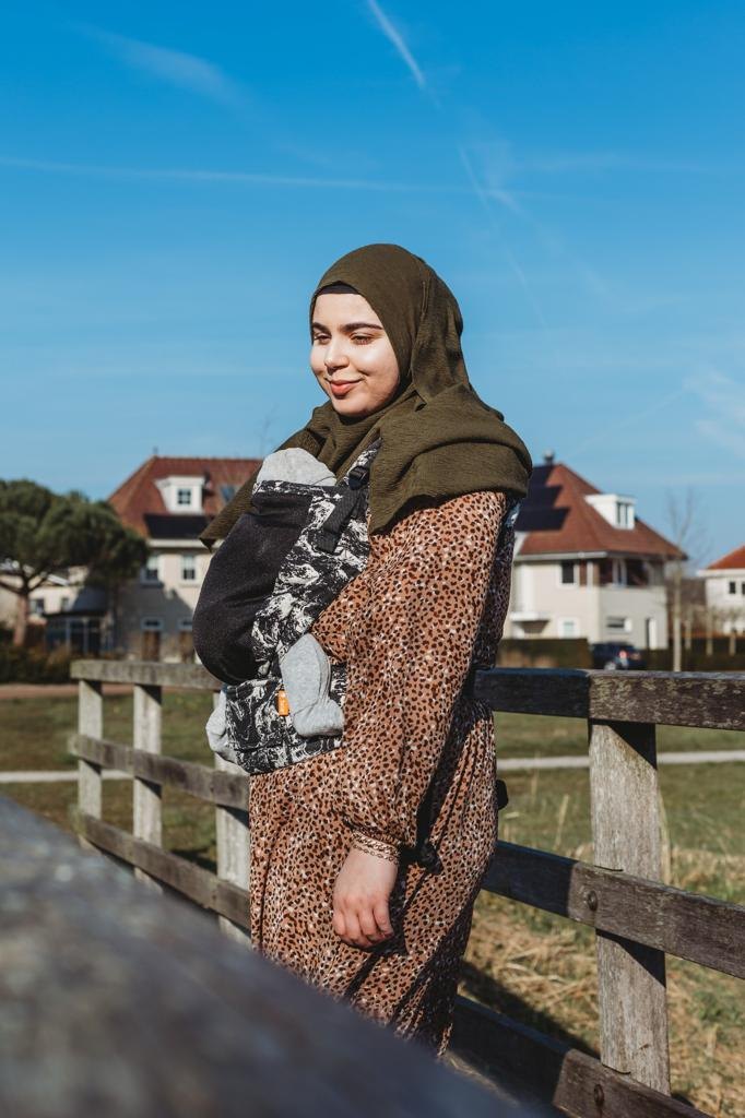 Feride staat glimlachend bij een houten hek